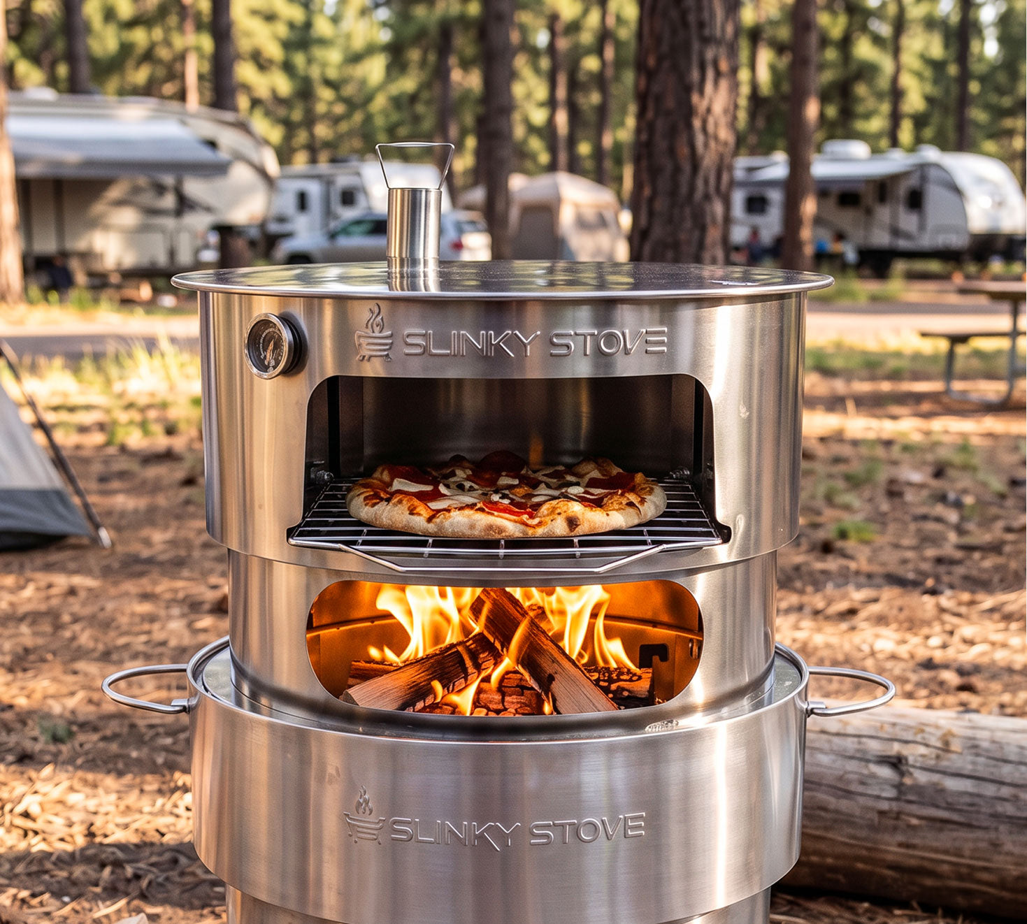 Slinky Stove pizza oven attachment mounted on the fire pit, cooking a pizza over a wood fire at an RV campsite.